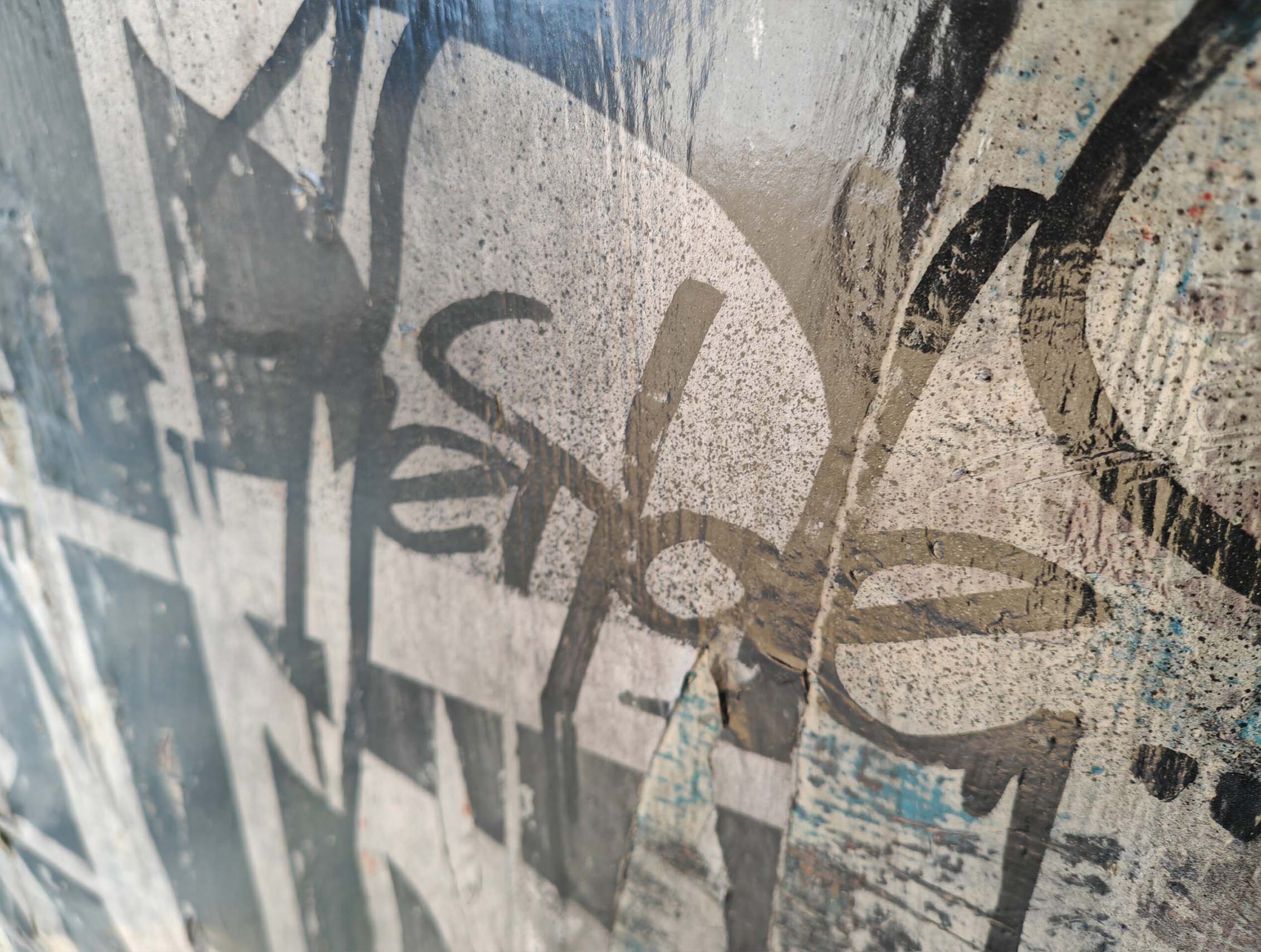 Putas sviluppa il linguaggio della calligrafia urbana attraverso una composizione monumentale e stratificata dove segni, abrasioni e sovrapposizioni costruiscono una superficie pittorica intensa e contemporanea. Il formato panoramico enfatizza la relazione tra scrittura, ritmo e spazio architettonico, mantenendo la tensione visiva tipica della ricerca di Kende.